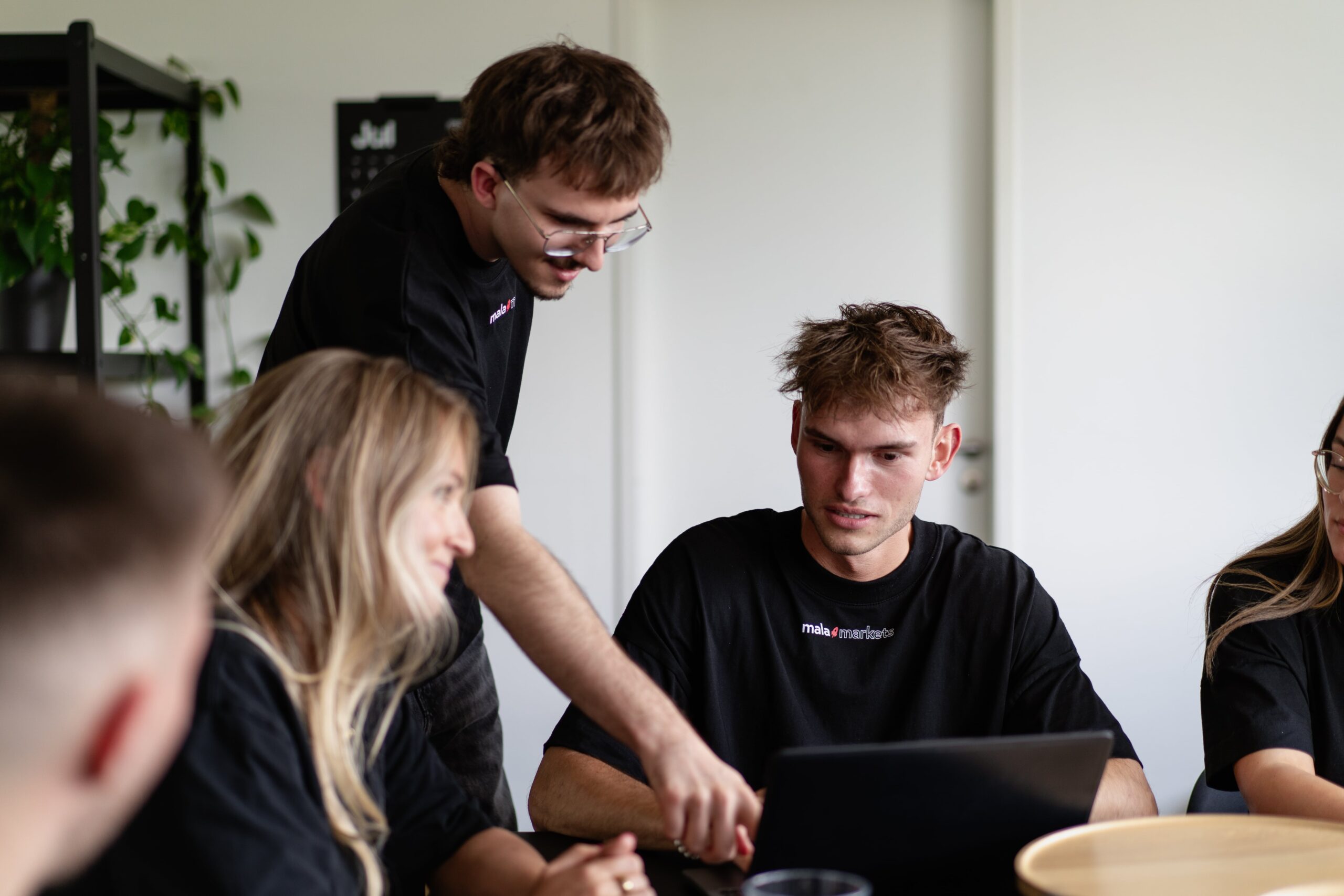 Personen arbeiten gemeinsam an einem Rechner im Büro