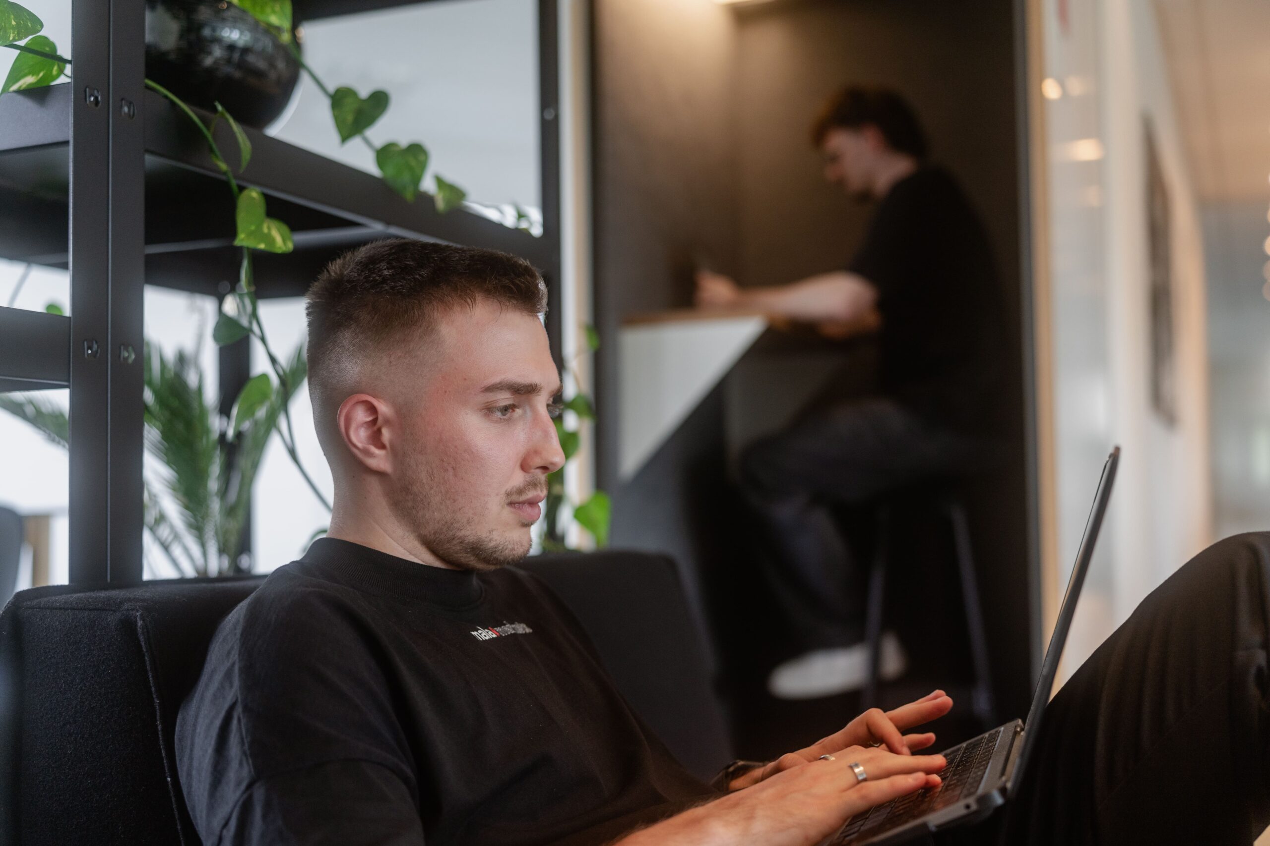 Mitarbeiter sitzt auf einem Sofa und arbeitet am Laptop